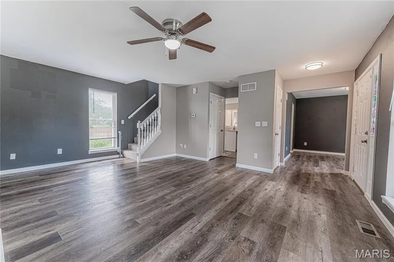 Wood-finish flooring throughout, ceiling fan with integrated lighting, painted staircase with white balusters, recessed lighting, and a white paneled door — 1721 Summergate Court, St Charles, MO 63303