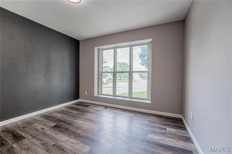 Wood-finish flooring with white trim, a large multi-pane window, and a contrasting accent wall — 1721 Summergate Court, St Charles, MO 63303