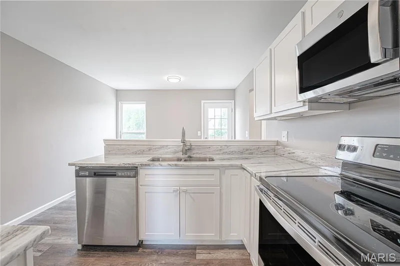 Kitchen featuring white cabinetry, stainless steel appliances, a double basin sink, and ample countertop space — 1721 Summergate Court, St Charles, MO 63303