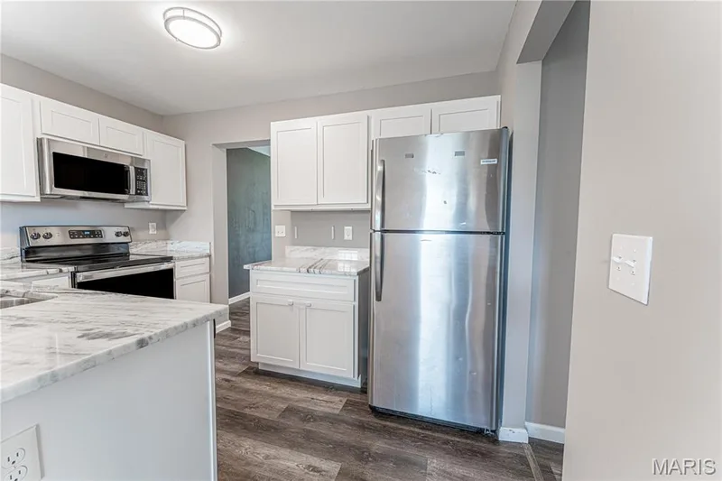White cabinetry, stainless steel appliances, speckled countertops, wood-finish flooring, and a flush mount ceiling light — 1721 Summergate Court, St Charles, MO 63303