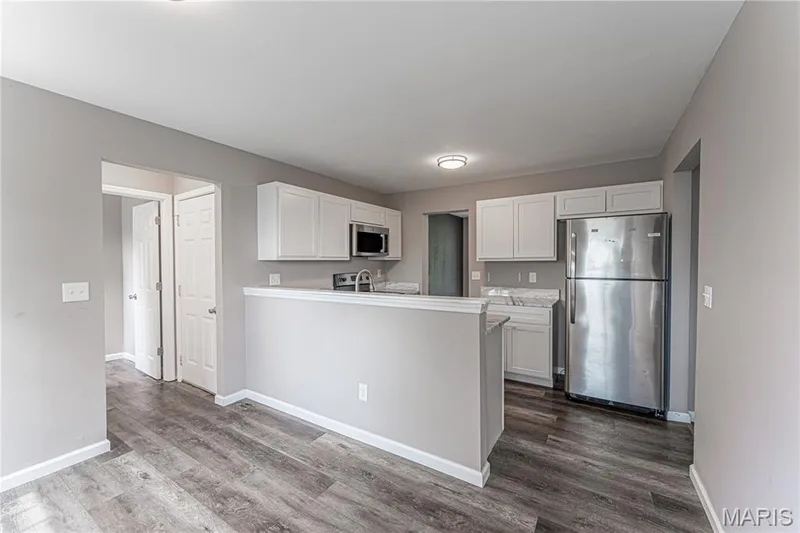 Kitchen featuring white cabinetry, stainless steel appliances, light-toned countertops, and wood-finish flooring — 1721 Summergate Court, St Charles, MO 63303