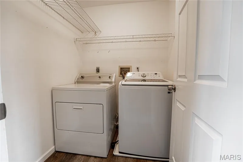 Laundry area featuring wire shelving, wood-finish flooring, and a white paneled door — 1721 Summergate Court, St Charles, MO 63303