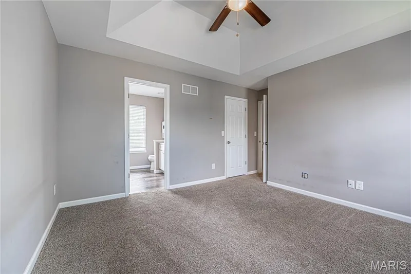 Tray ceiling with a ceiling fan, neutral wall paint, and carpet flooring — 1721 Summergate Court, St Charles, MO 63303