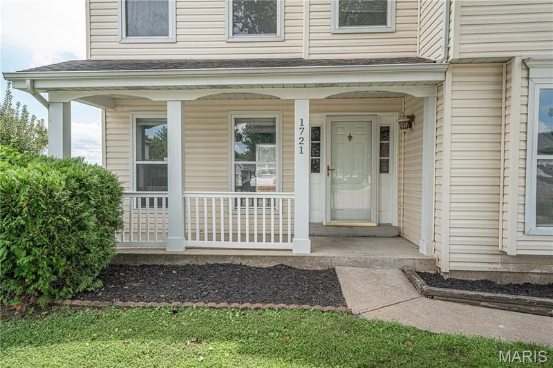 Covered front porch with white railings, white front door with decorative glass inserts, and light-colored siding — 1721 Summergate Court, St Charles, MO 63303