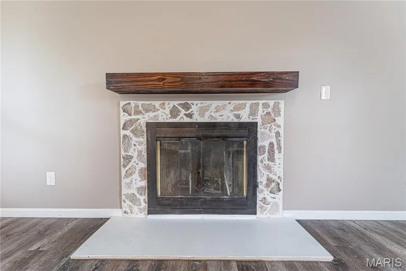 Fireplace featuring a stone surround, a dark wood mantel, and a neutral hearth — 1721 Summergate Court, St Charles, MO 63303