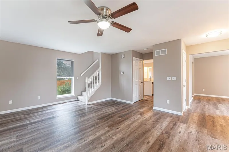 Wood-finish flooring, staircase with carpeted treads, ceiling fan with integrated lighting, and neutral wall tones — 1721 Summergate Court, St Charles, MO 63303