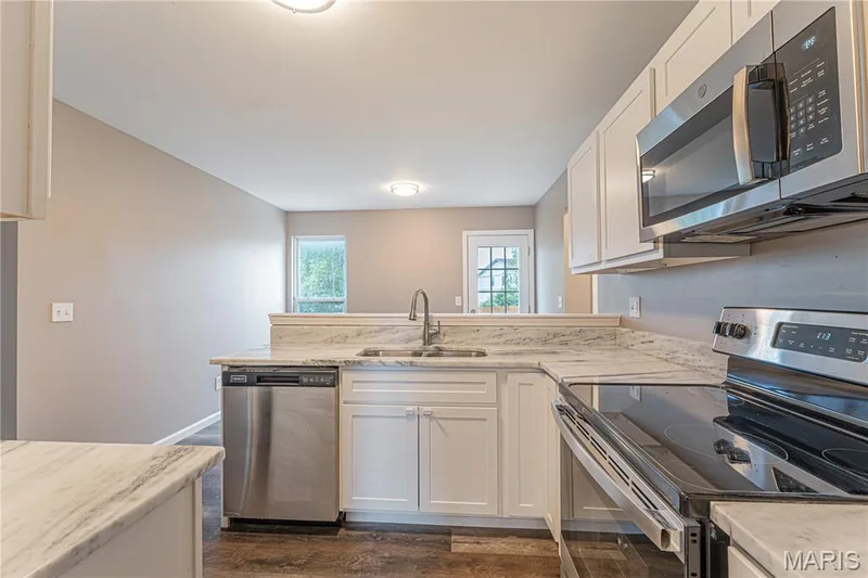 Kitchen featuring white cabinetry, stainless steel appliances, a stainless steel sink, and light-toned countertops — 1721 Summergate Court, St Charles, MO 63303