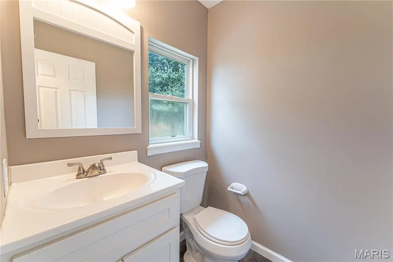 White vanity with integrated sink, brushed nickel faucet, framed mirror, and a window — 1721 Summergate Court, St Charles, MO 63303