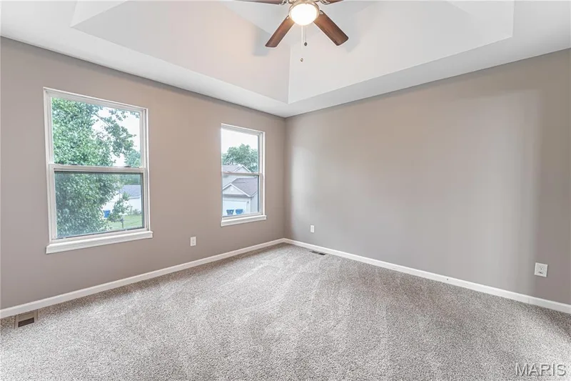 Tray ceiling with a ceiling fan, two windows, and neutral carpeting — 1721 Summergate Court, St Charles, MO 63303