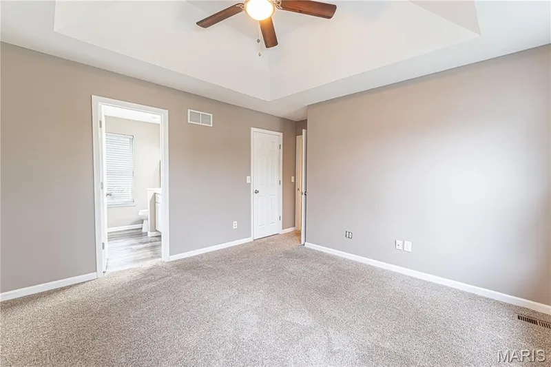 Tray ceiling with a ceiling fan, neutral wall paint, and plush carpet flooring — 1721 Summergate Court, St Charles, MO 63303