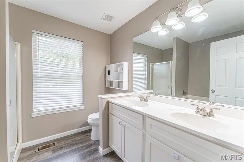 Double vanity with integrated sinks, brushed nickel faucets, and a large wall-mounted mirror — 1721 Summergate Court, St Charles, MO 63303