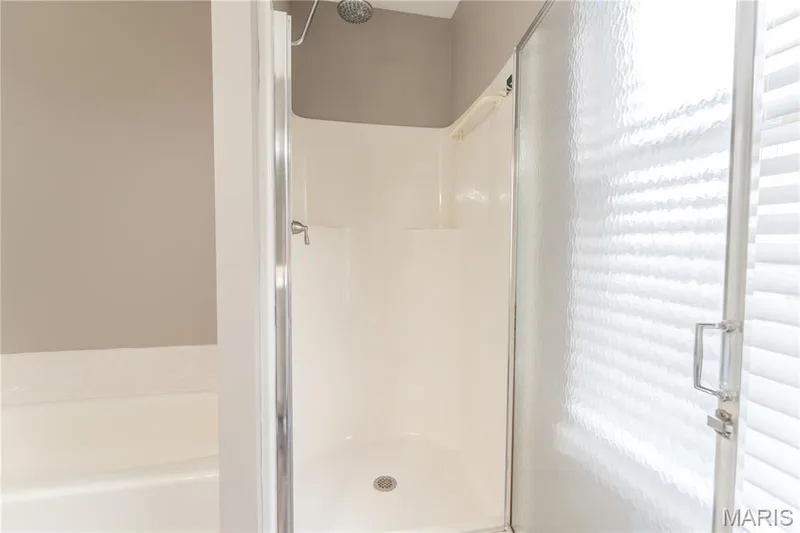 Walk-in shower with a chrome shower head, textured glass door, and integrated shelving — 1721 Summergate Court, St Charles, MO 63303