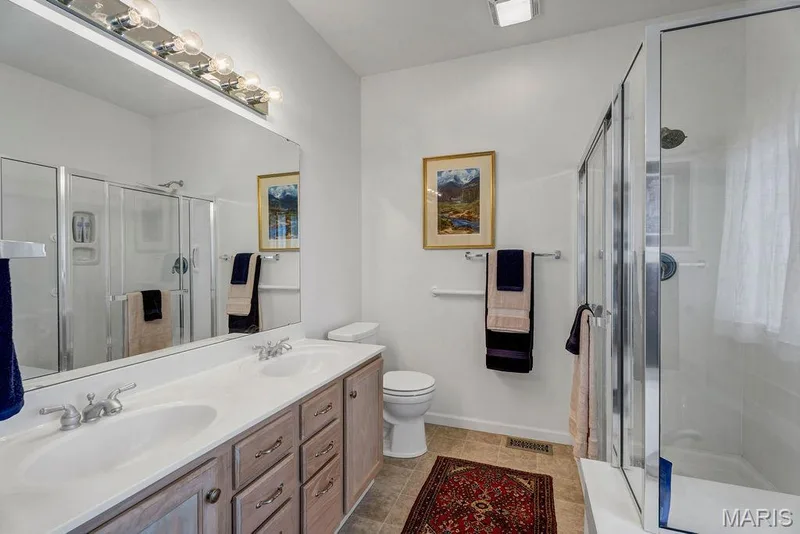 Ensuite bathroom features dual sinks and a generous shower stall with a bench for convenience. — 781 Queens Court Place, St Peters, MO 63376
