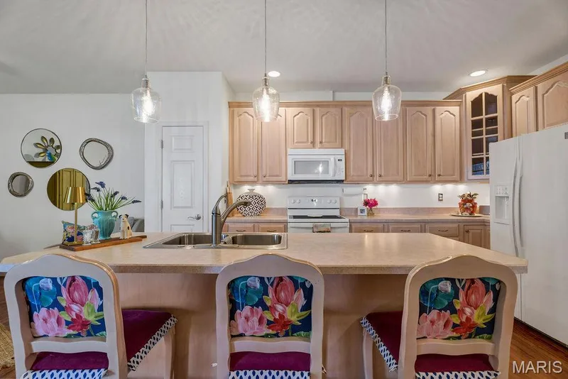 Beautiful pendant lighting combined with can lights AND under cabinet lighting makes this space light and bright. And, I want to point out...the door on the left is the full-size pantry! — 781 Queens Court Place, St Peters, MO 63376