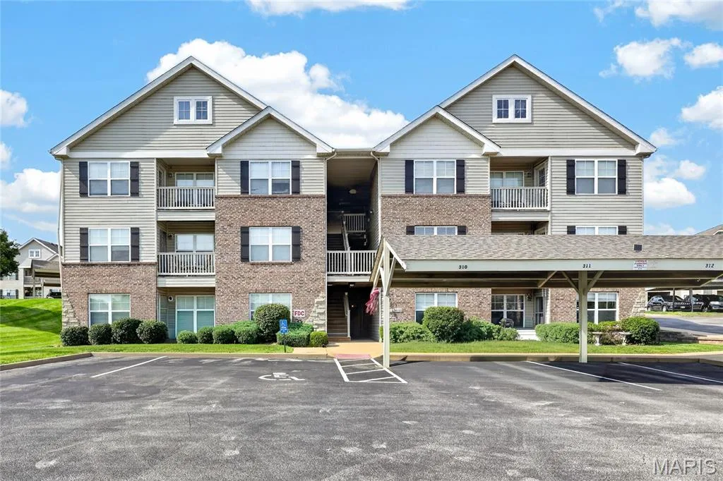 Multi-unit residential building featuring brick and vinyl siding exterior with pitched rooflines, multiple covered entry porches with railings, and symmetrical architectural design — 313 Bramblett Hills, O'Fallon, MO 63366