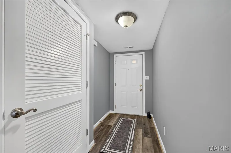 Wood-finish flooring with a flush-mount ceiling light fixture, white interior door, and louvered door with a brushed nickel handle — 313 Bramblett Hills, O'Fallon, MO 63366