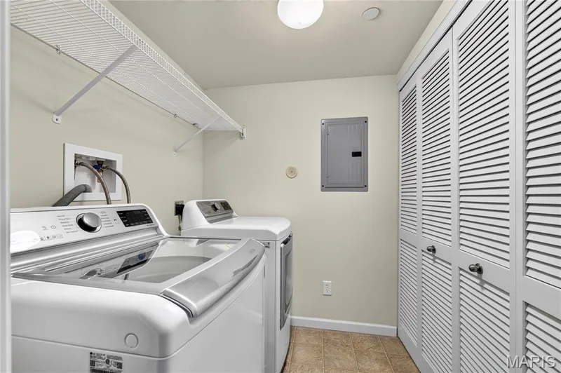 Laundry area featuring a built-in wire shelf, louvered bi-fold doors, and neutral-toned flooring — 313 Bramblett Hills, O'Fallon, MO 63366