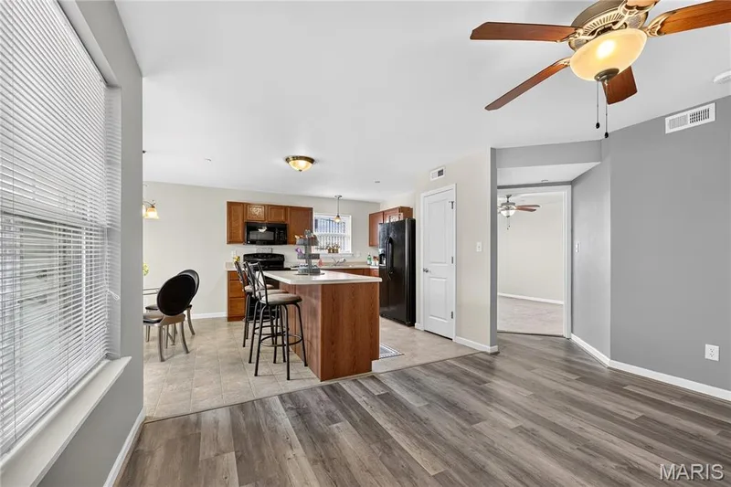 Kitchen featuring wood cabinetry, stainless steel appliances, and a central island with countertop seating — 313 Bramblett Hills, O'Fallon, MO 63366