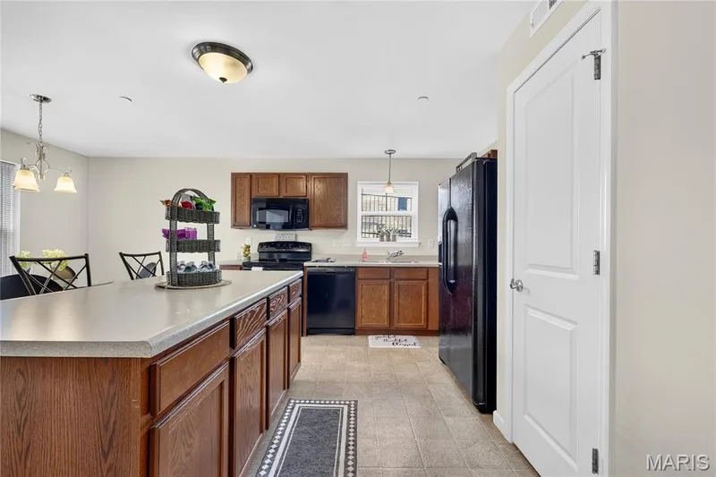 Kitchen featuring wood cabinetry, black appliances, a central island with a light-toned countertop, and recessed lighting — 313 Bramblett Hills, O'Fallon, MO 63366