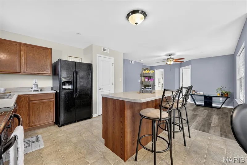 Kitchen featuring wood cabinetry, light-toned countertops, and a central island with seating — 313 Bramblett Hills, O'Fallon, MO 63366