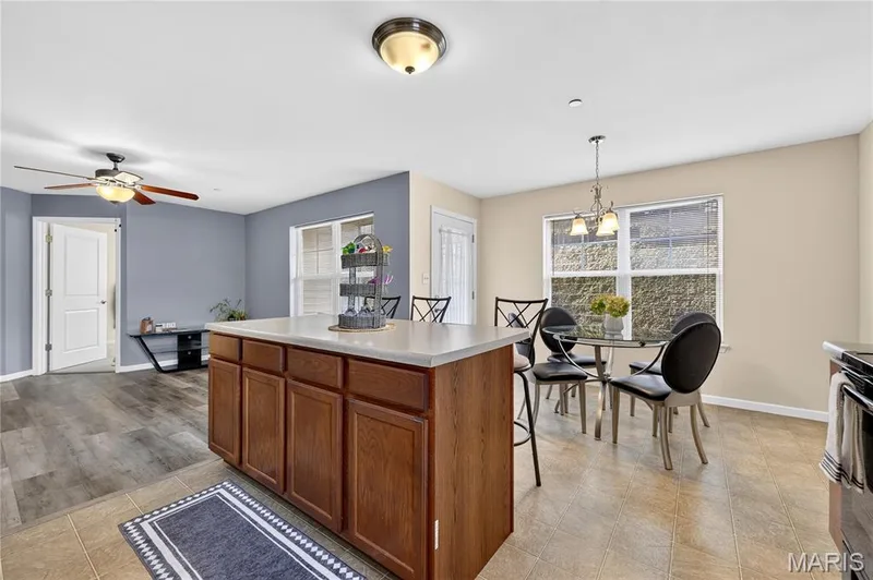 Kitchen island with cabinet storage, tile flooring, and a dining area — 313 Bramblett Hills, O'Fallon, MO 63366