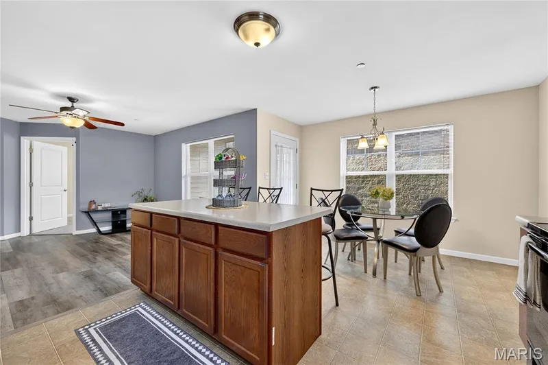 Central kitchen island with wood-finish cabinetry and light-toned countertop — 313 Bramblett Hills, O'Fallon, MO 63366