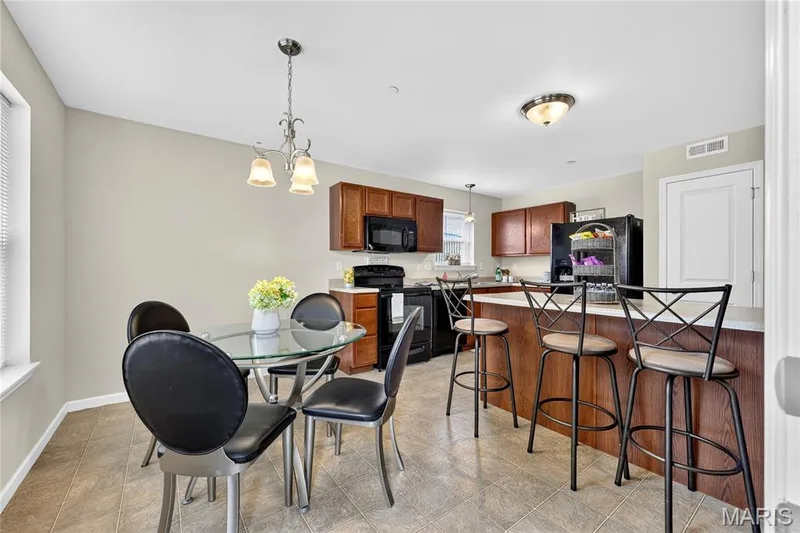 Kitchen featuring wood cabinetry, integrated appliances, a breakfast bar, and tile flooring — 313 Bramblett Hills, O'Fallon, MO 63366
