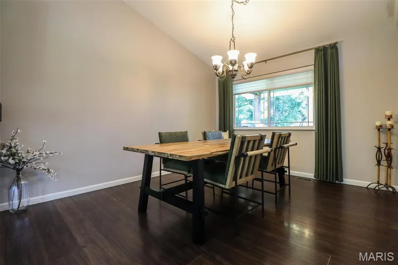 Dining room features vaulted ceiling with an overhead chandelier and dark luxury vinyl plank flooring — 12 Pyrenees Drive, Lake St. Louis, MO 63367
