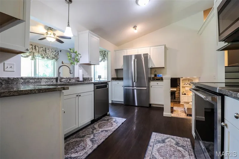 Kitchen featuring white custom cabinetry, stainless steel appliances, and granite counters — 12 Pyrenees Drive, Lake St. Louis, MO 63367