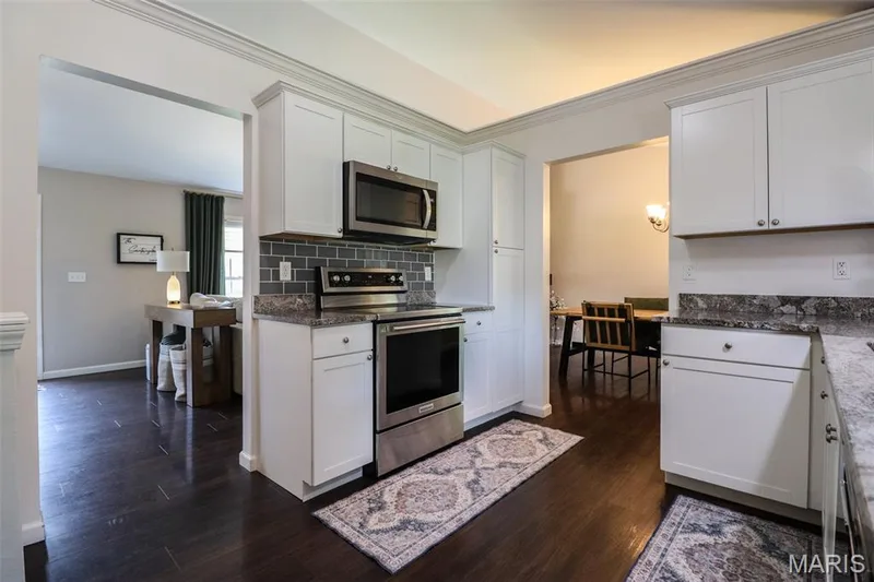 Kitchen featuring white custom cabinetry, stainless steel appliances, and granite counters — 12 Pyrenees Drive, Lake St. Louis, MO 63367