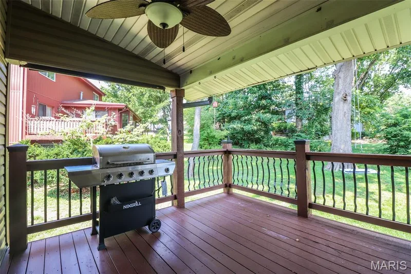 Covered wood deck featuring a ceiling fan and decorative black railings — 12 Pyrenees Drive, Lake St. Louis, MO 63367