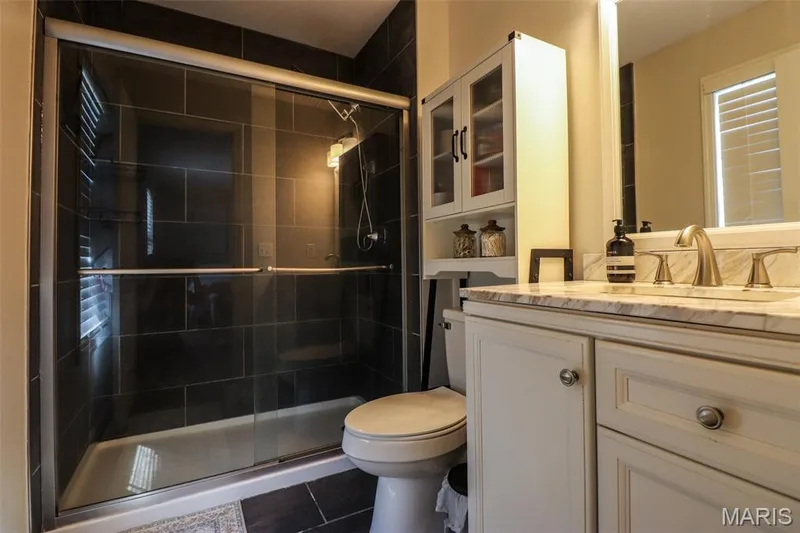 Primary bathroom with black tile flooring, walk-in shower and updated vanity — 12 Pyrenees Drive, Lake St. Louis, MO 63367