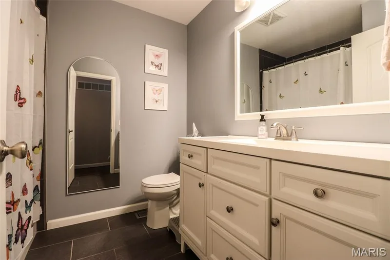 Bathroom featuring black tile floors, large vanity with storage and tub/shower combo — 12 Pyrenees Drive, Lake St. Louis, MO 63367
