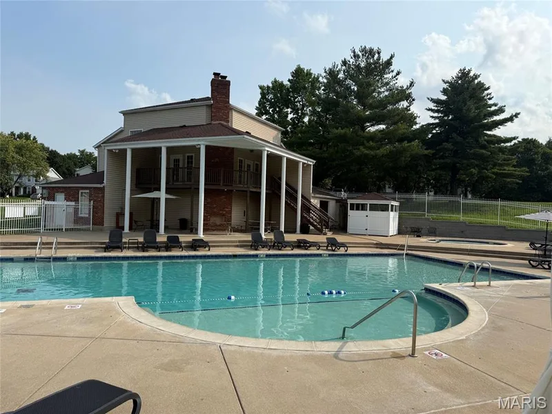 Neighborhood Recreation Center - Expansive concrete pool deck featuring a swimming pool, integrated spa, and a pool house structure — 303 Whispering Woods Drive, St Peters, MO 63304