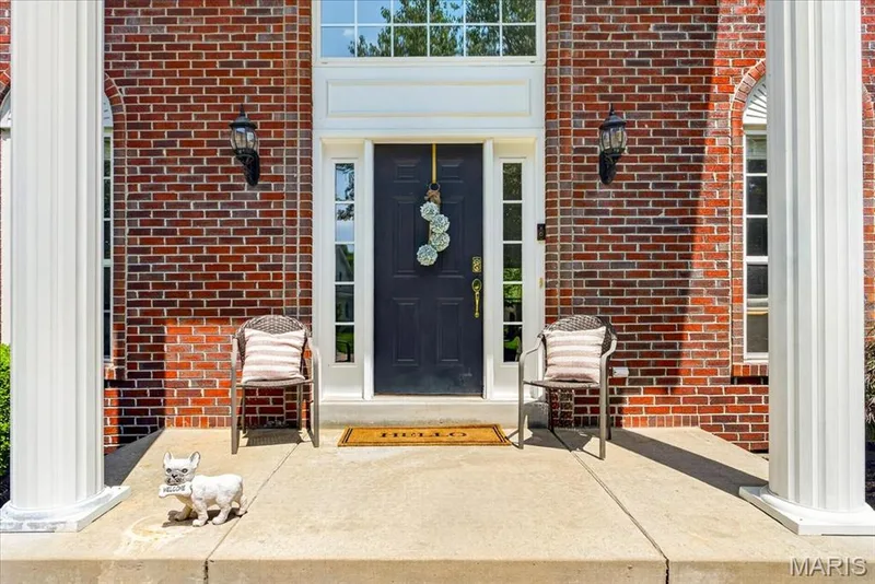 Brick exterior featuring a paneled front door with sidelights, transom window, and architectural columns — 17821 Wilderness Cliff Court, Wildwood, MO 63005