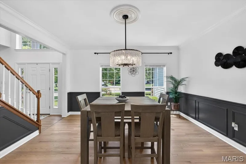 Spacious dining area featuring wood-finish flooring, wainscoting, and a decorative chandelier — 17821 Wilderness Cliff Court, Wildwood, MO 63005