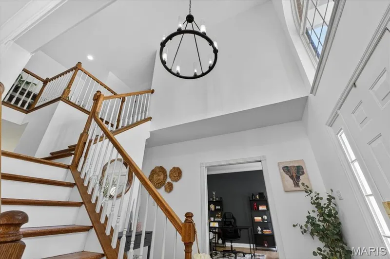 Two-story foyer featuring a grand staircase with wood treads and white balusters — 17821 Wilderness Cliff Court, Wildwood, MO 63005
