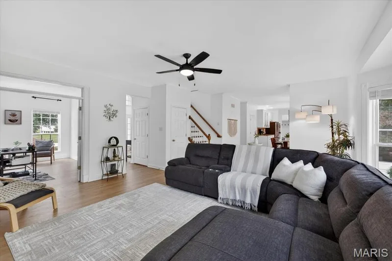 Spacious living area featuring light wood-finish flooring, a contemporary ceiling fan, and crisp white walls — 17821 Wilderness Cliff Court, Wildwood, MO 63005
