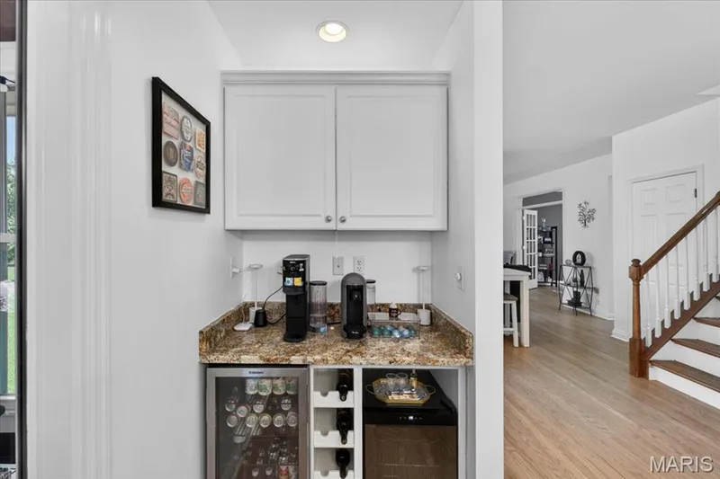 Built-in beverage station featuring white cabinetry, a stone-finish countertop, and integrated wine storage — 17821 Wilderness Cliff Court, Wildwood, MO 63005
