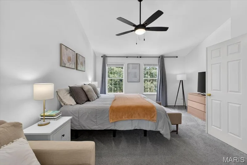 Spacious room featuring vaulted ceilings, a contemporary ceiling fan, and two large windows offering natural light — 17821 Wilderness Cliff Court, Wildwood, MO 63005