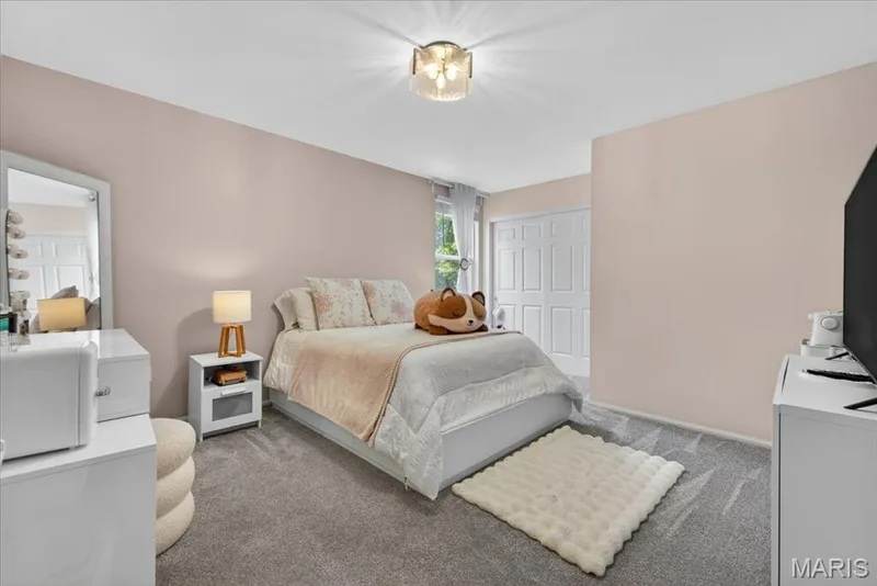 Bedroom featuring light-colored walls, gray carpeting, a window with sheer curtains, a white paneled door, and a flush-mount ceiling light fixture — 17821 Wilderness Cliff Court, Wildwood, MO 63005