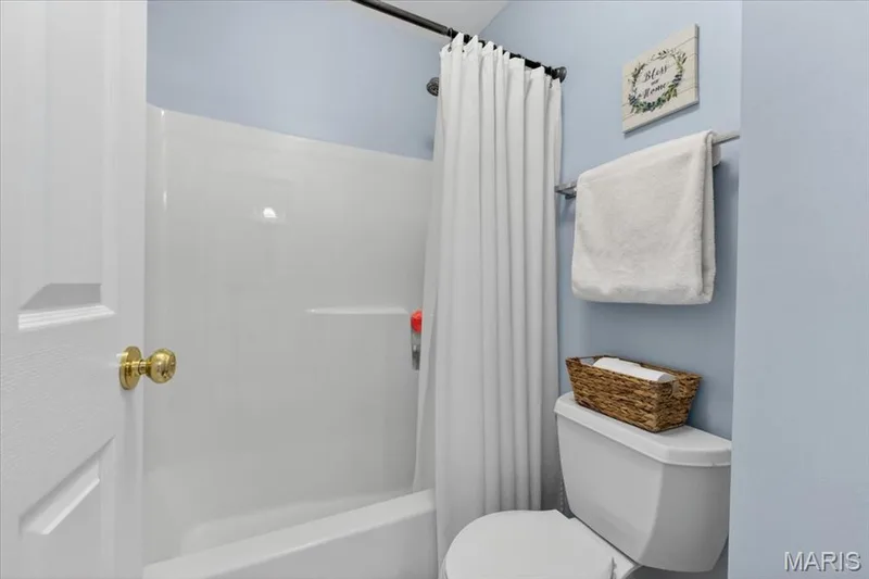 Bathroom featuring a white tub-shower combination, a standard toilet, and light blue wall paint — 17821 Wilderness Cliff Court, Wildwood, MO 63005