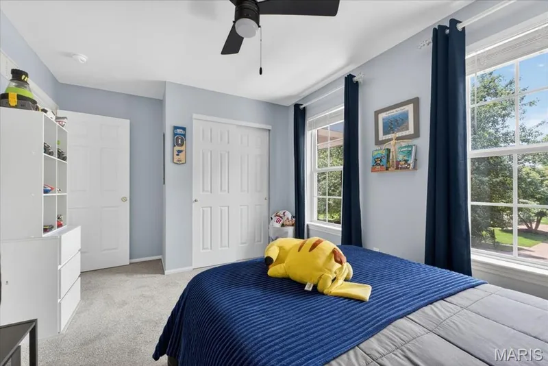 Bedroom featuring two large windows, light gray carpeting, and a ceiling fan — 17821 Wilderness Cliff Court, Wildwood, MO 63005