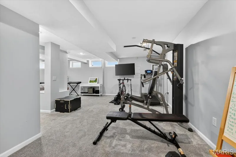 Spacious lower-level room featuring light gray carpeting, recessed lighting, white trim, and multiple egress windows — 17821 Wilderness Cliff Court, Wildwood, MO 63005