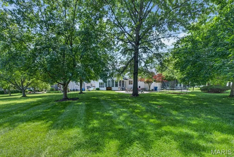 Expansive rear yard featuring mature trees, a lush lawn, and a light-toned exterior with multiple windows — 17821 Wilderness Cliff Court, Wildwood, MO 63005