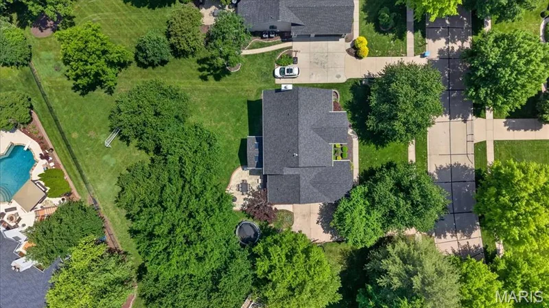 Expansive property featuring a dark-shingled roofline, multiple mature trees, a broad green lawn, and a paved driveway — 17821 Wilderness Cliff Court, Wildwood, MO 63005