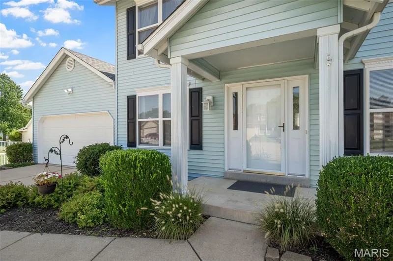 Light blue siding exterior with white trim, covered front porch, attached garage, and mature landscaping — 120 Bromley Court, O'Fallon, MO 63368
