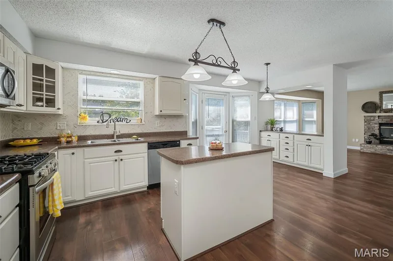 Kitchen featuring wood-finish flooring, white cabinetry, a central island, and stone countertops — 120 Bromley Court, O'Fallon, MO 63368