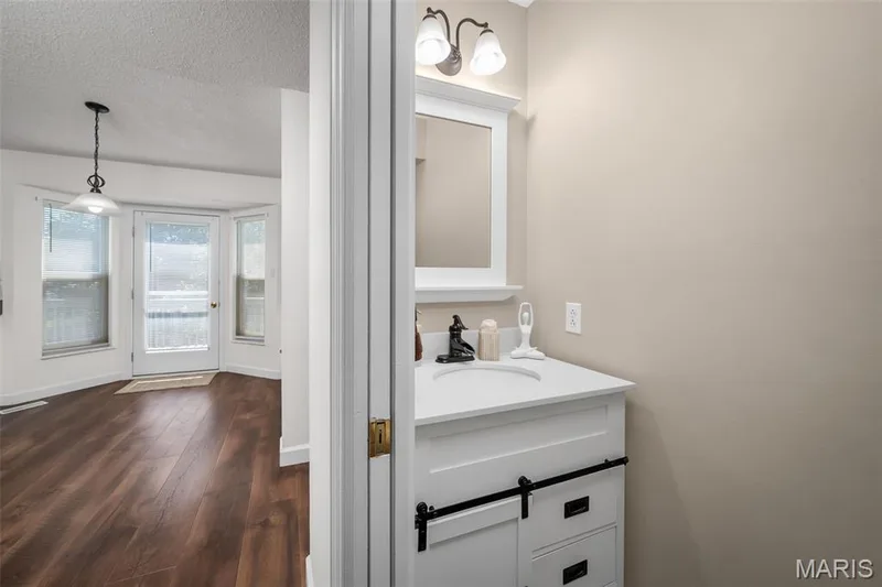 White vanity with a single basin sink and wall-mounted mirror — 120 Bromley Court, O'Fallon, MO 63368