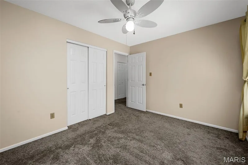 Neutral-toned walls and ceiling, ceiling fan with integrated lighting, wall-to-wall carpeting, and white bi-fold closet doors — 120 Bromley Court, O'Fallon, MO 63368